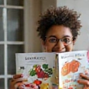 Un'immagine di una persona che impara con gioia sulla sana alimentazione, magari leggendo un libro o guardando un'infografica con verdure e frutta, con un senso di scoperta e curiosità.